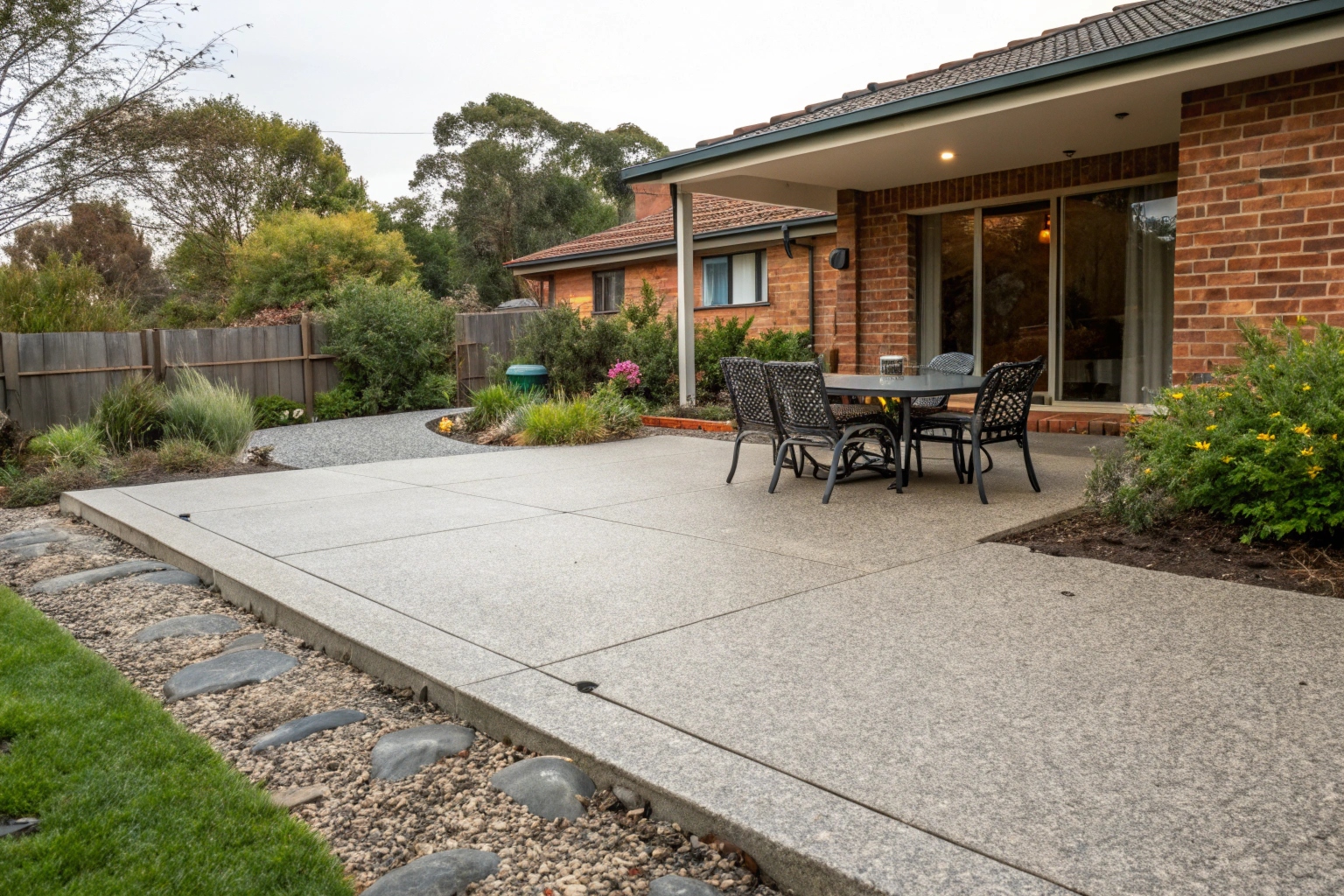 a-freshly-completed-exposed-aggregate-concrete-pat Exposed aggregate concrete patio slab with outdoor dining setup behind Newcastle home
