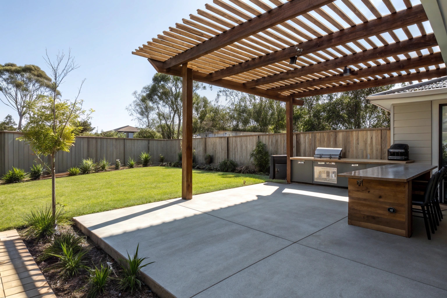 Concrete patio slab under timber pergola with outdoor kitchen in Newcastle backyard
